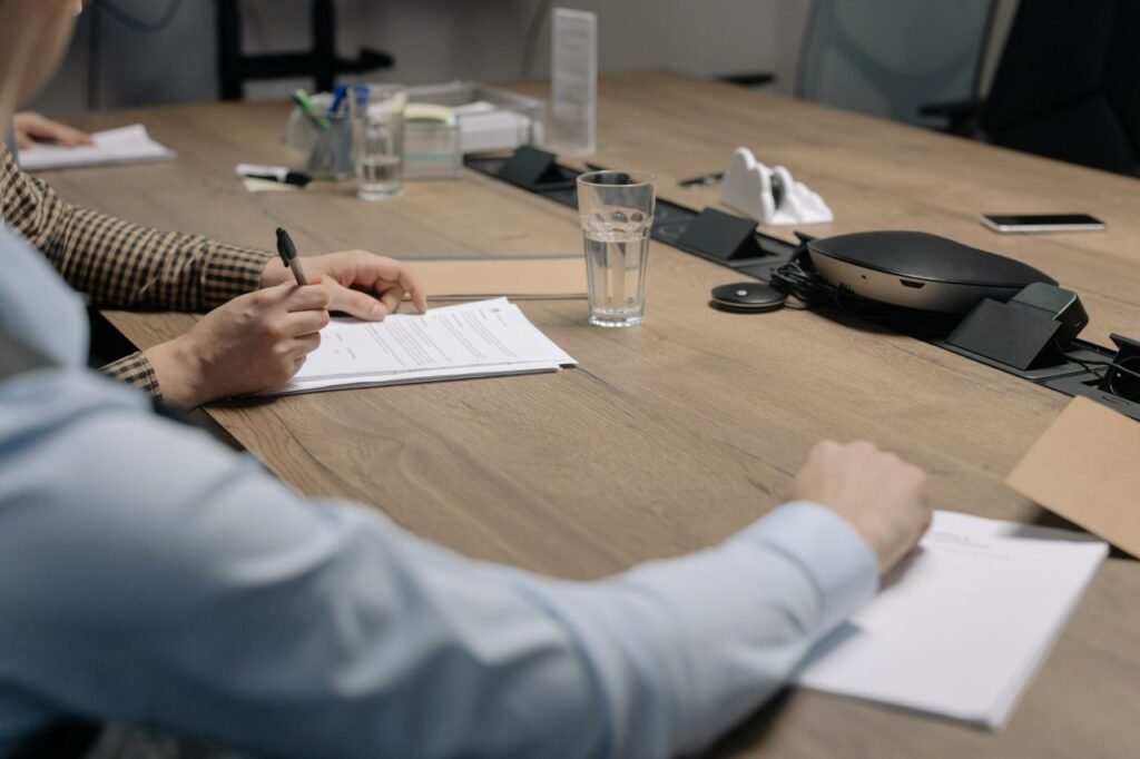 Professional setting of a business meeting with individuals signing documents on a conference table.